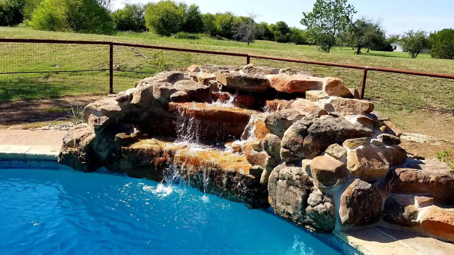 Waterfall water feature added to pool in landscape in China Spring, TX.
