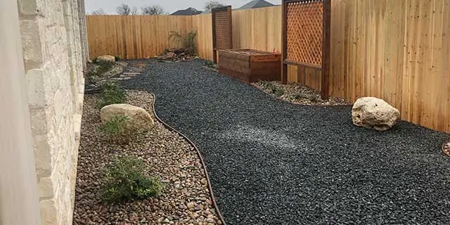 Woodway, Texas property with rock mulch landscaping and wooden fence.