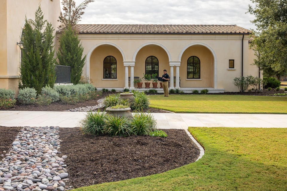 Account manager inspecting residential property landscape beds water runoff plants