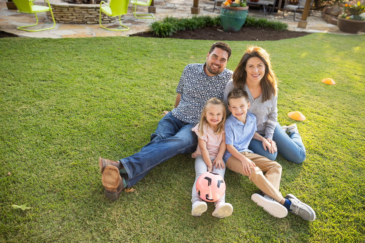 Family customers kids sitting on green lawn 