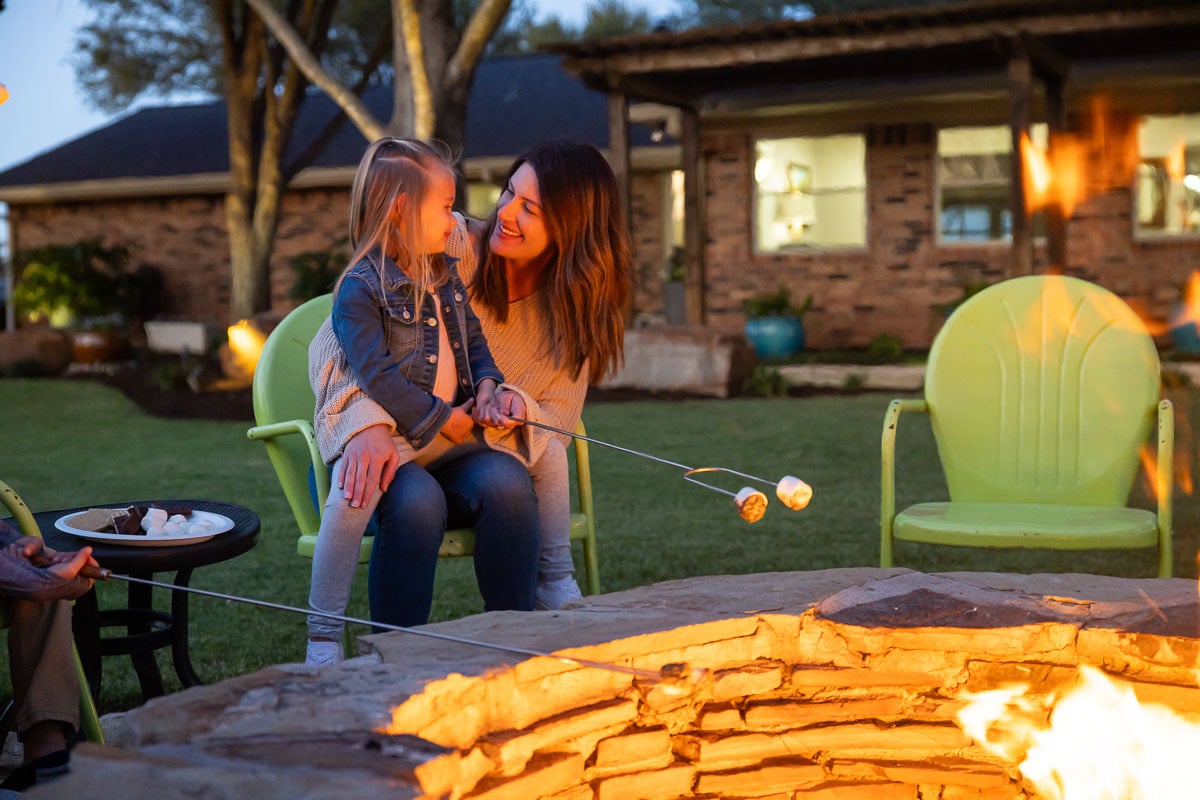 Family roasting marshmellows fire feature green lawn 