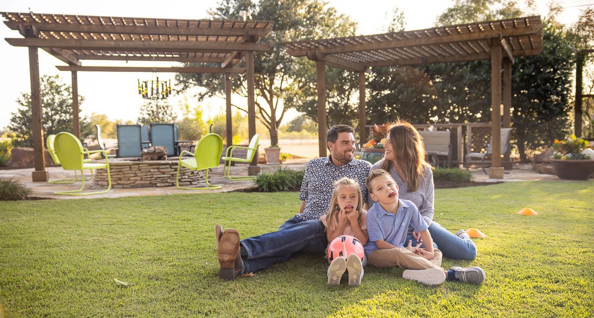 Family customers kids sitting in green lawn patio pergola fire pit socker ball 