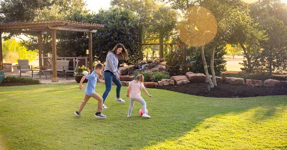 Kids playing socker green lawn pergola landscaping beds 6