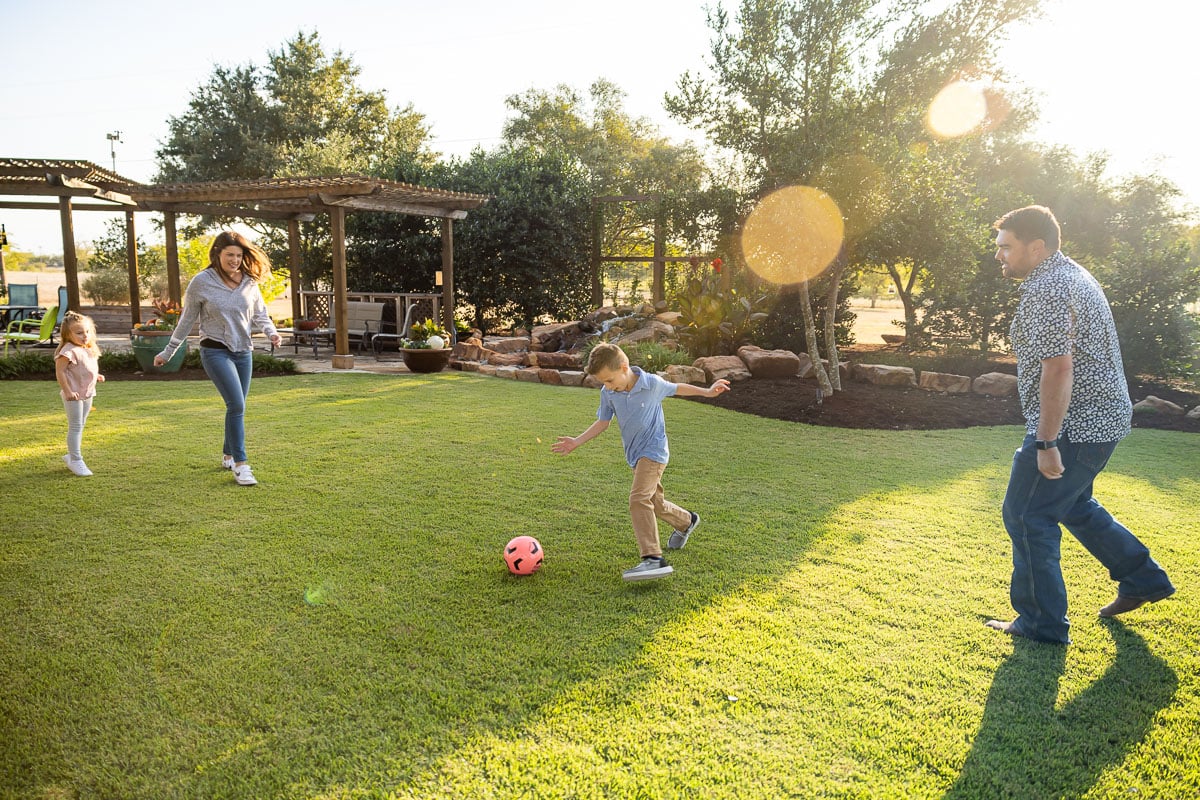 Kids playing socker green lawn pergola landscaping beds 10