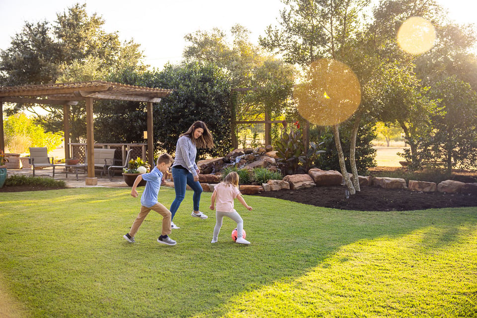 Kids playing socker green lawn pergola landscaping beds 6