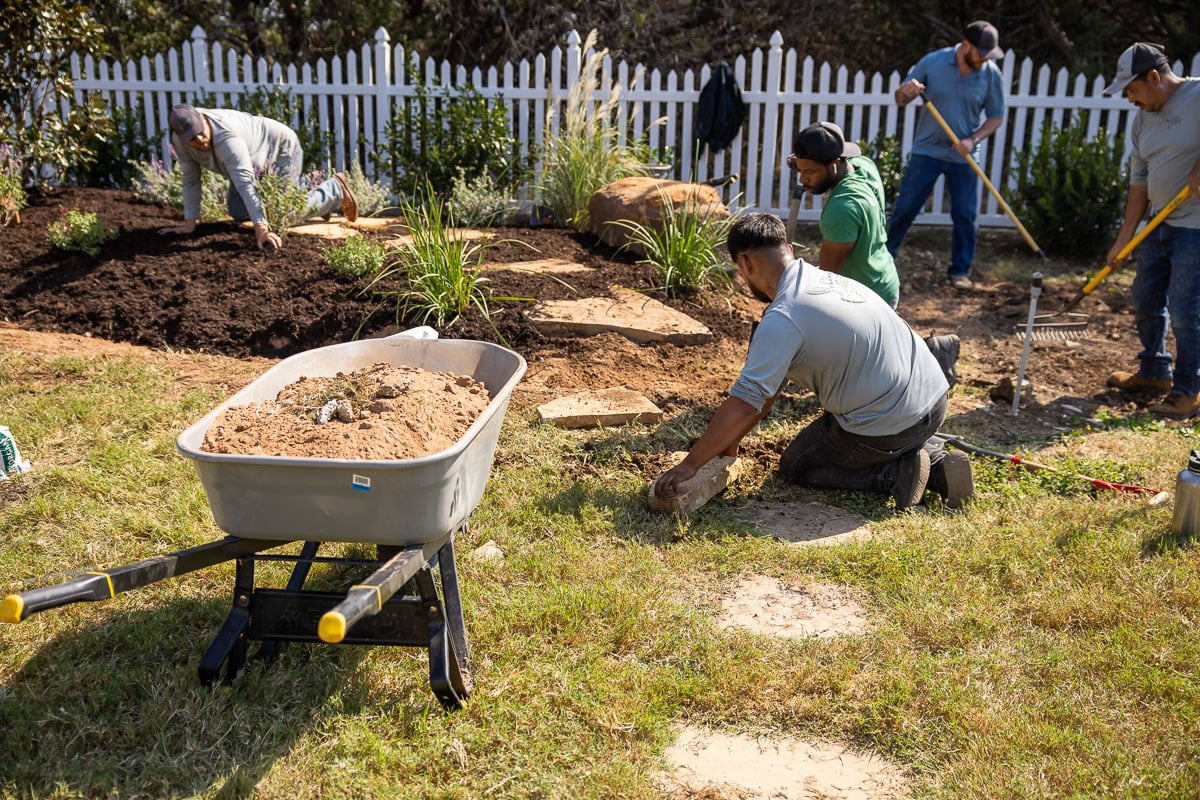 Landscape installation shrubs planted along fence paver walkway installed crew 