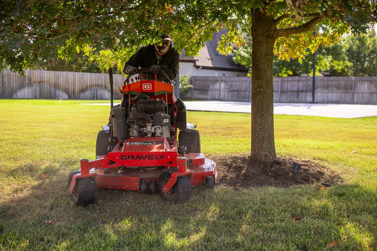 Residential landscape maintenance crew mowing backyard green lawn