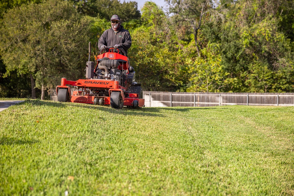 Residential landscape maintenance crew mowing backyard green lawn 4