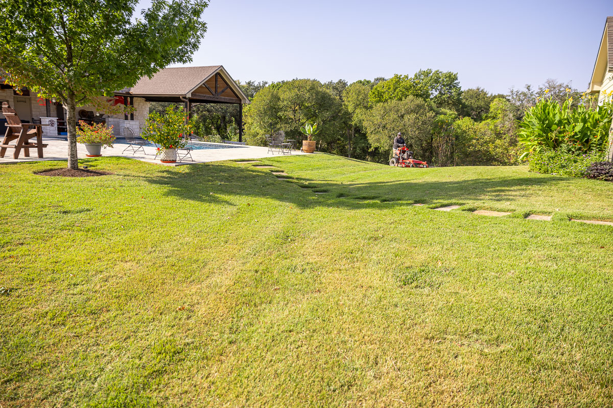 Residential landscape maintenance crew mowing backyard patio green lawn