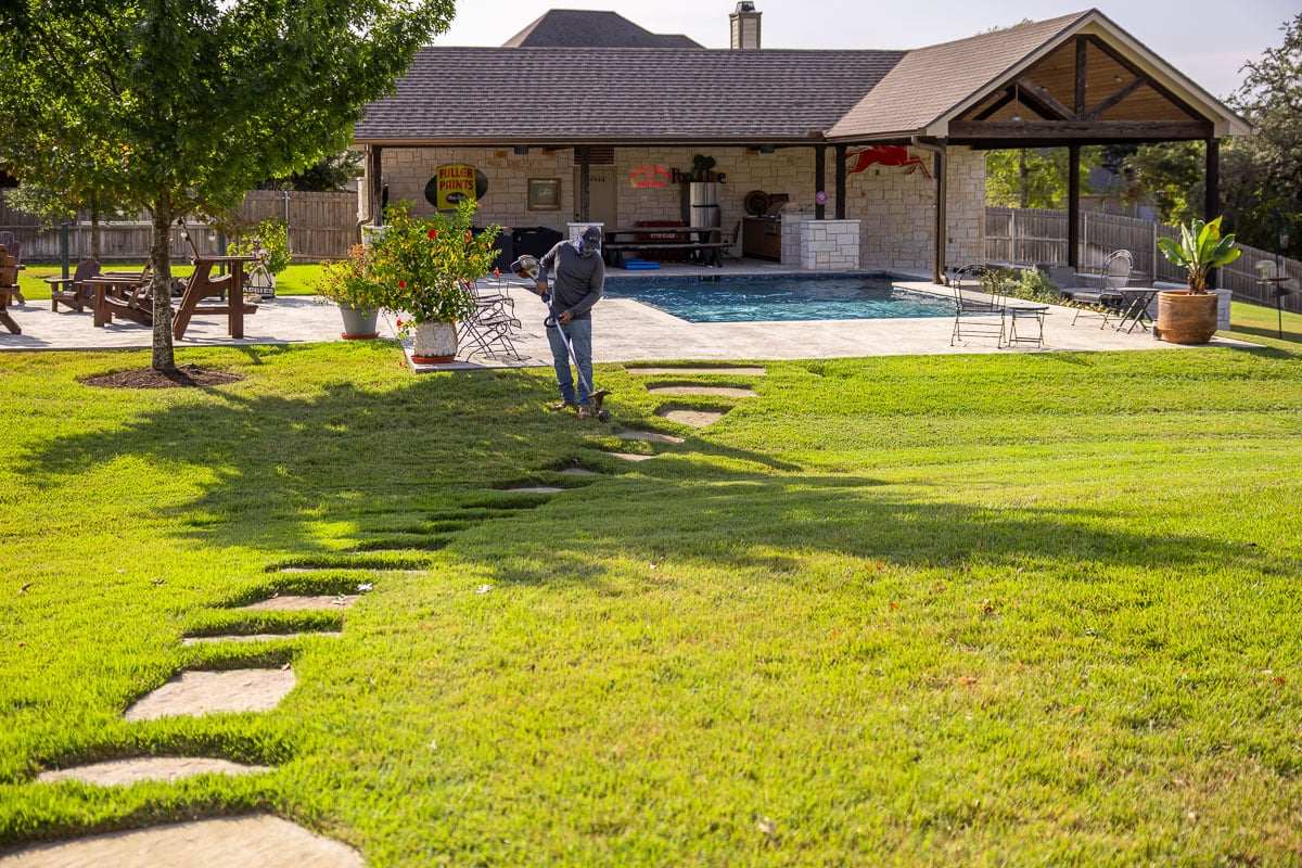 Residential landscape maintenance crew weed wacking  backyard green lawn pool patio 4
