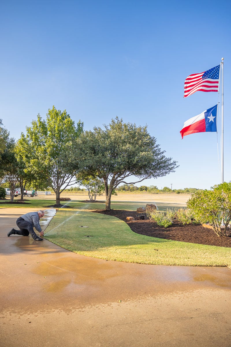 Residential maintenance irrigation sprinklers watering lawn flags technician adjusting sprinkler head 1