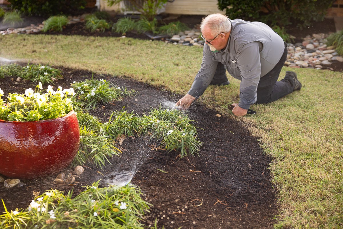 Residential maintenance irrigation sprinklers watering lawn technician adjusting sprinkler heads 2