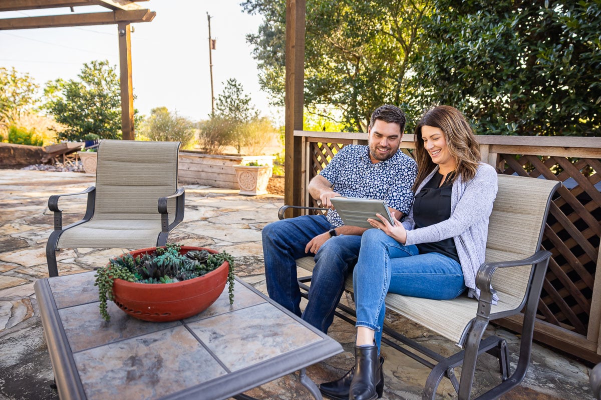 customers sitting on patio looking at tablet 