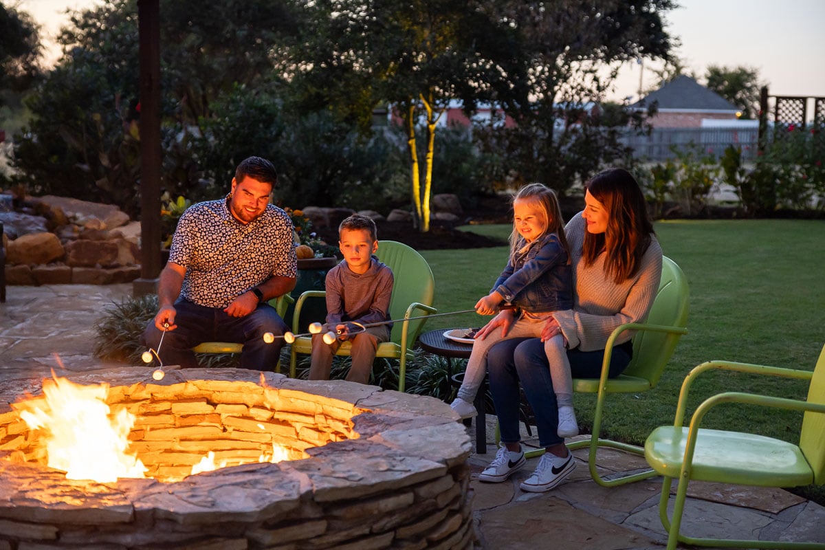 family customers roasting marshmellows bonfire green lawn patio