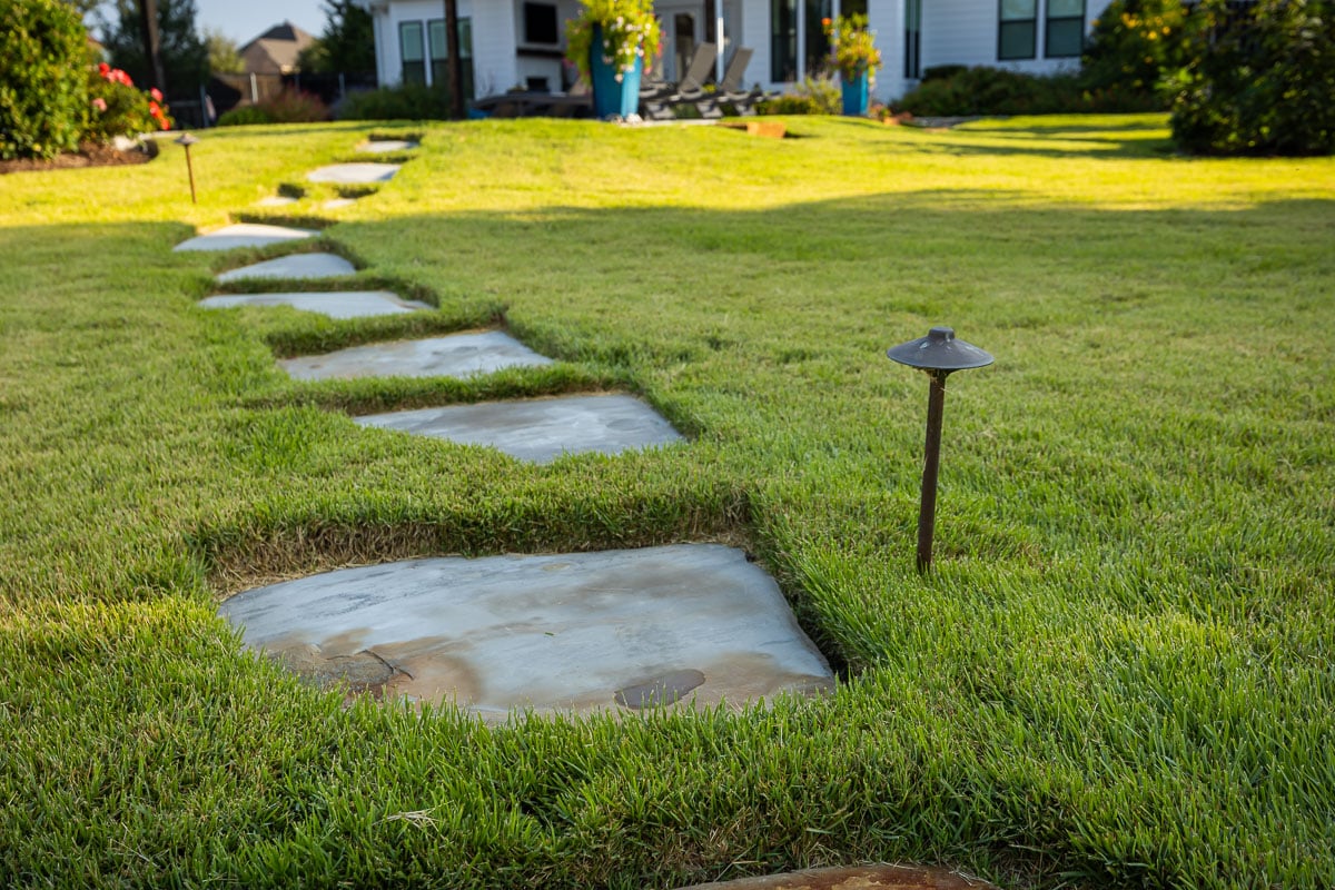 paver walkway landscape lighting green lawn backyard