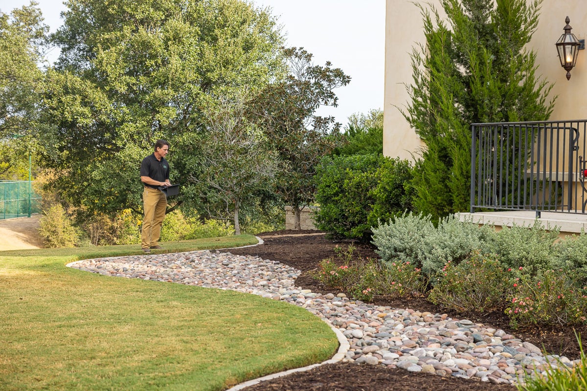 Account manager inspecting residential property landscape beds mulch plants 