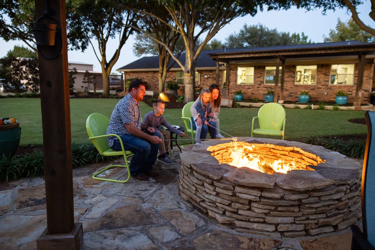 Fire feature family customers roasting marshmellows green lawn backyard