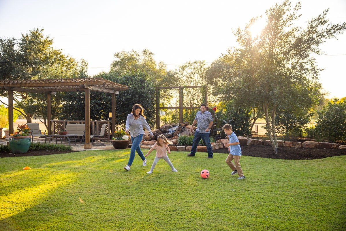 Kids playing socker green lawn pergola landscaping beds 8