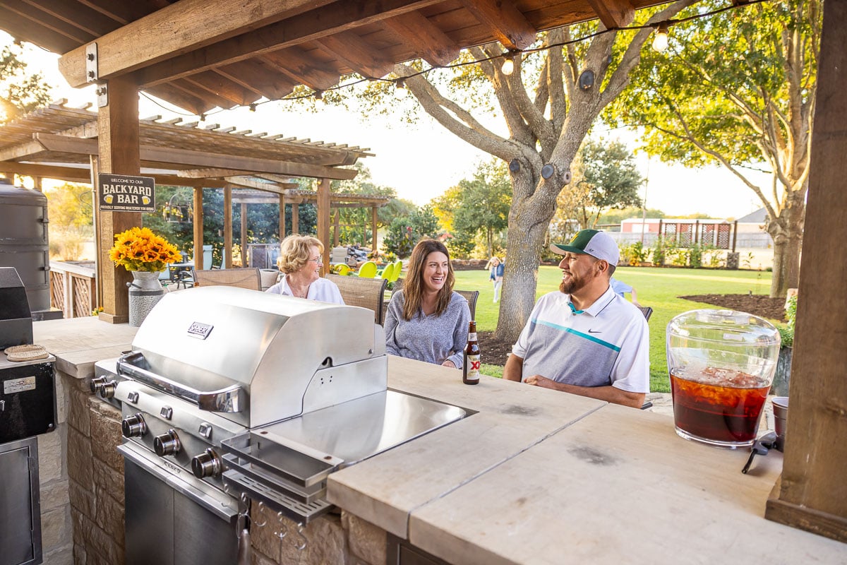 Outdoor kitchen family backyard green lawn pergola 