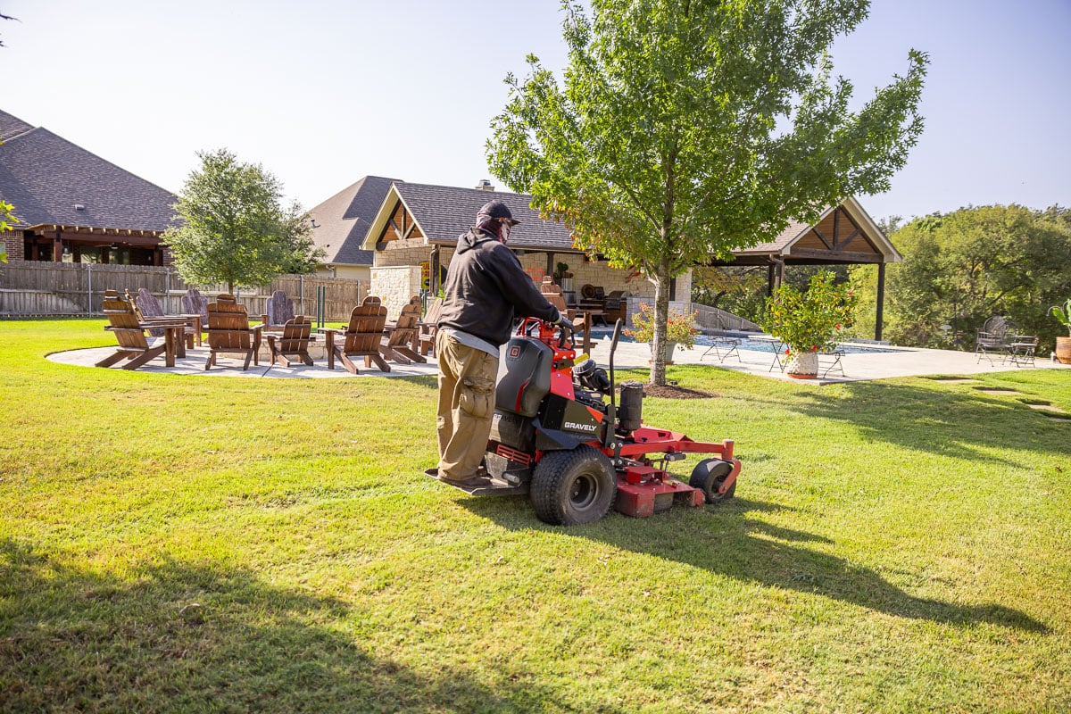 Residential landscape maintenance crew mowing backyard patio green lawn 1