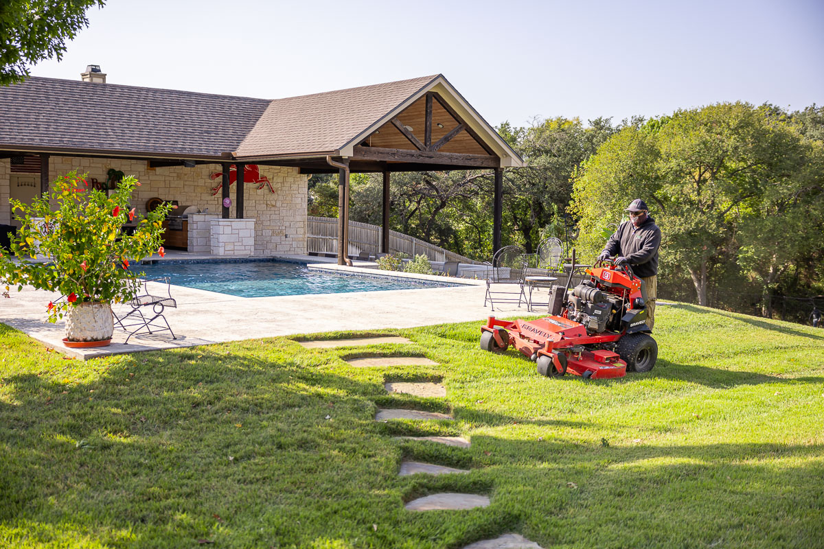 Residential landscape maintenance crew mowing backyard pool patio green lawn 